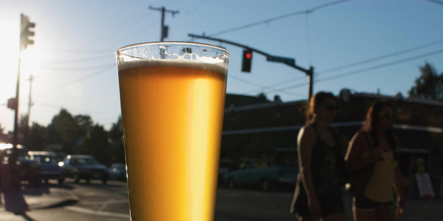 Pint of craft beer in sunlight with urban street background, goruck.mommunity vibe