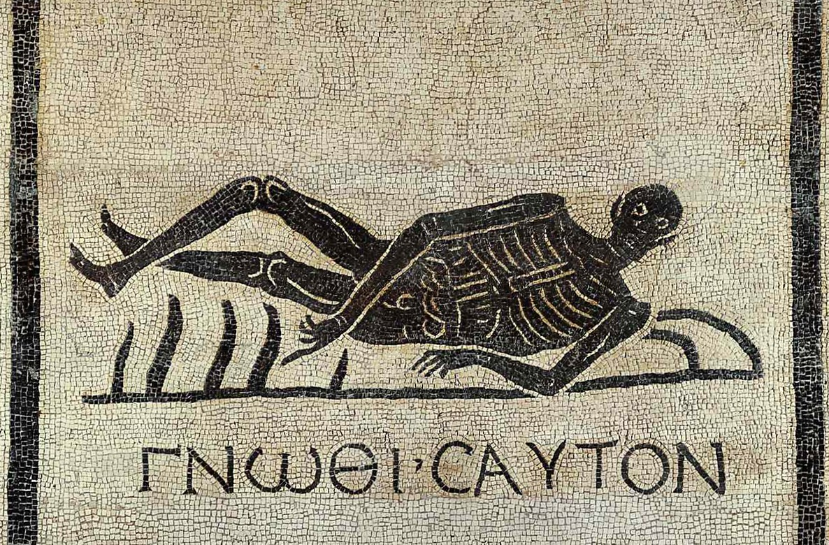 Ancient mosaic art of a reclining skeleton with Greek text, on a stone tile background
