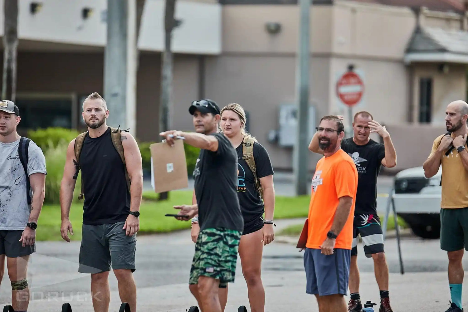 GORUCK group training outdoors, participants in athletic gear with rucksacks preparing for event