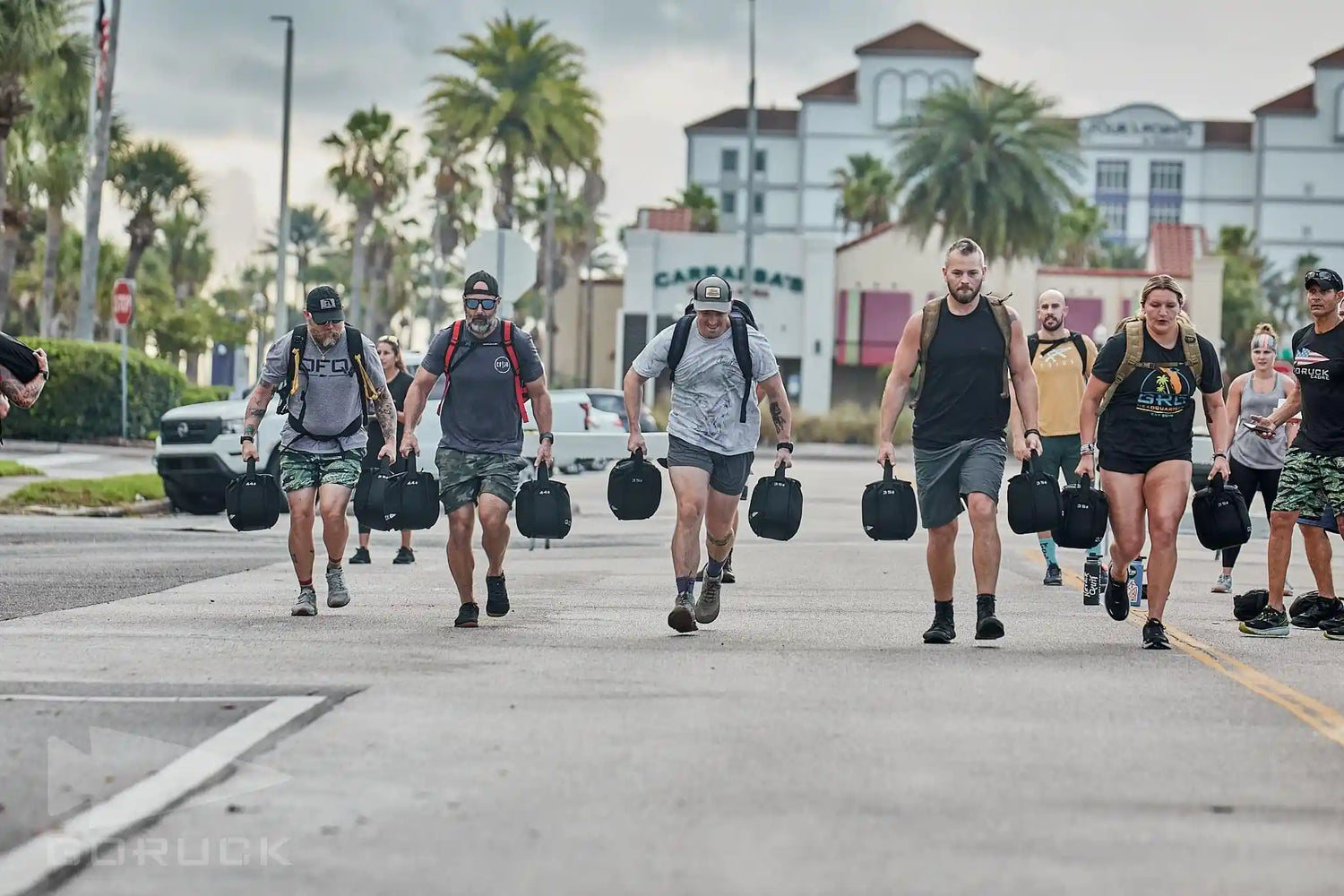 Group of people rucking outdoors with GORUCK gear, carrying weighted sandbags in city setting