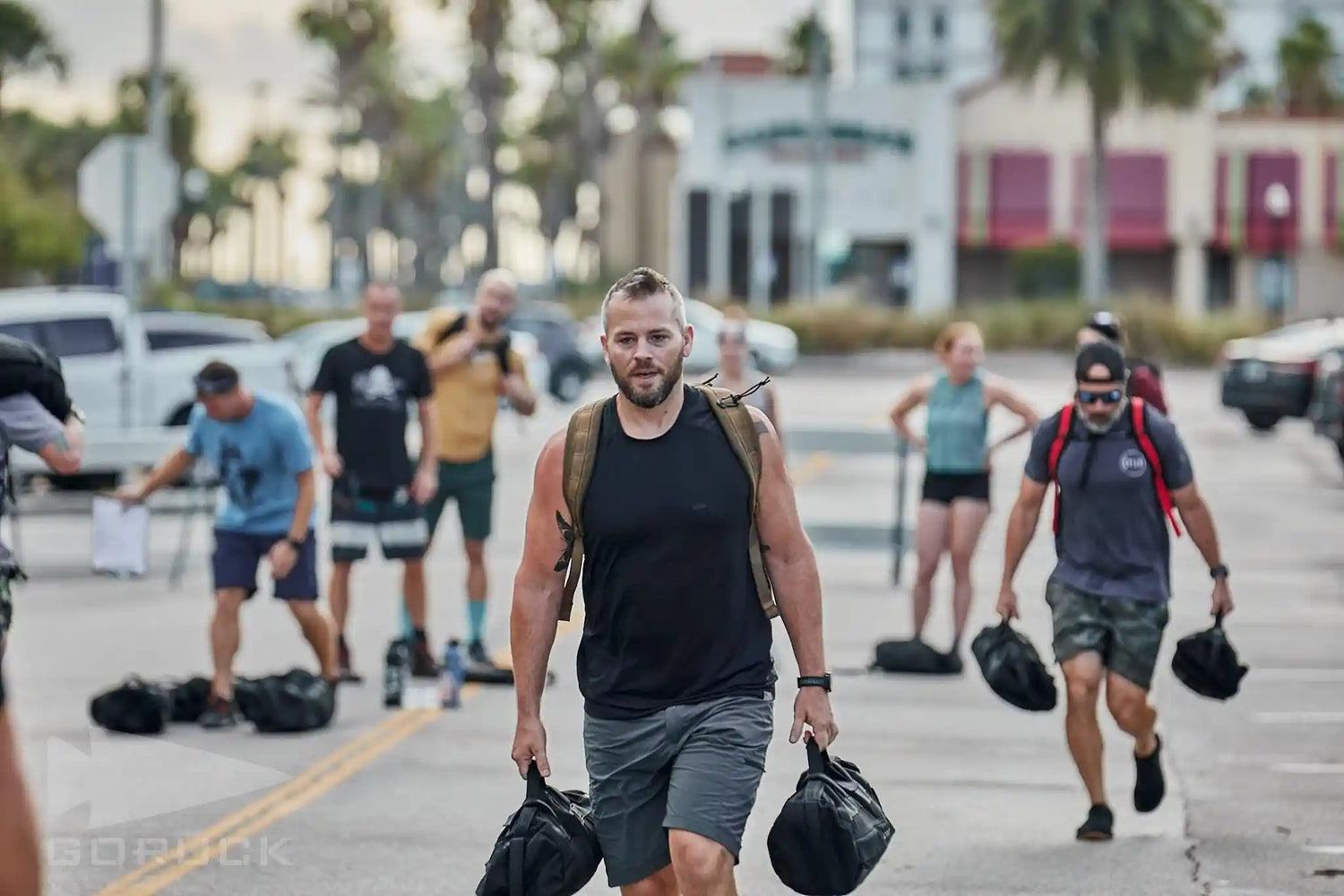 Group of people rucking outdoors with GORUCK gear and sandbags on city street