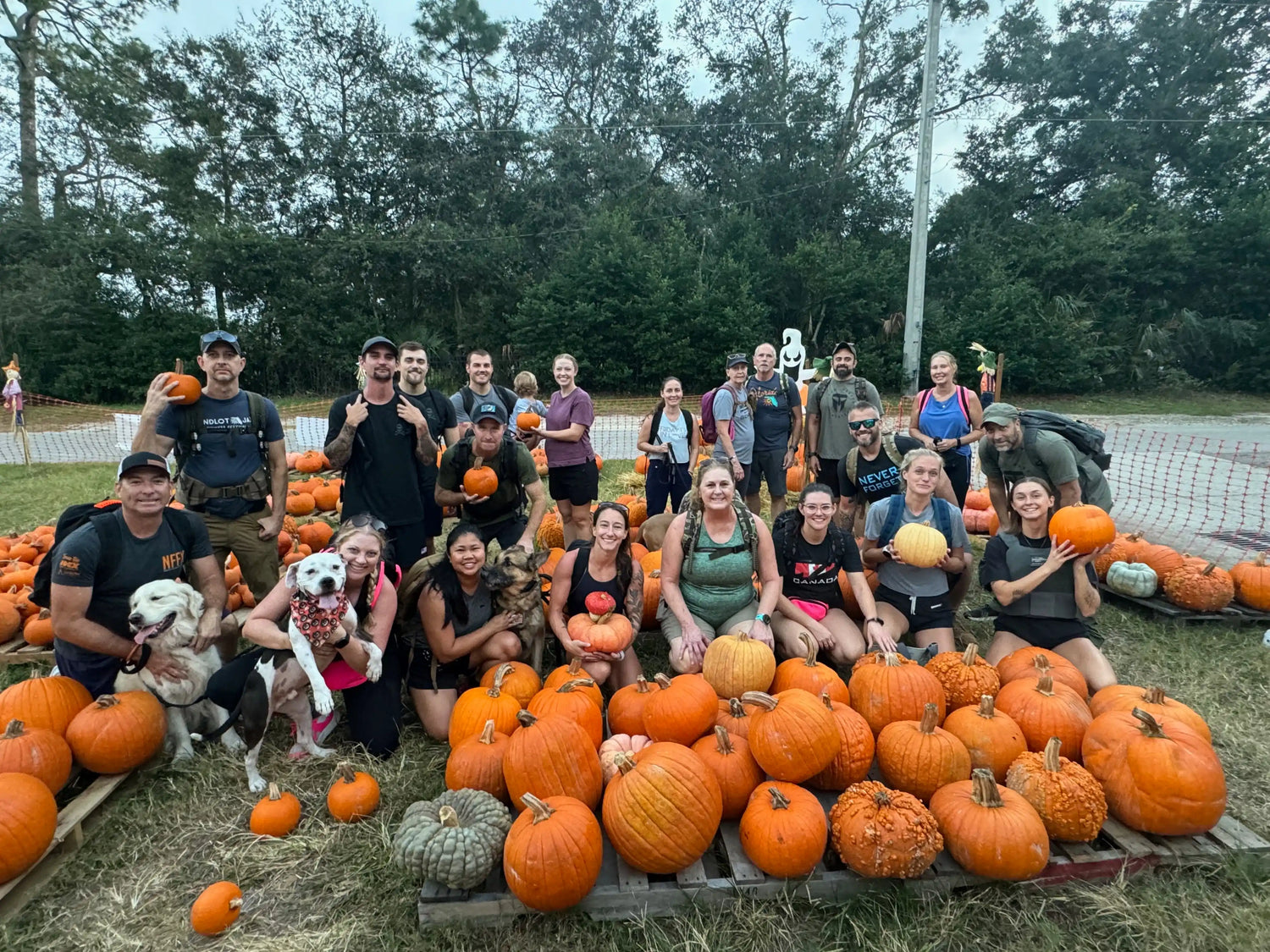 GORUCK group with backpacks and dogs posing at outdoor pumpkin patch event