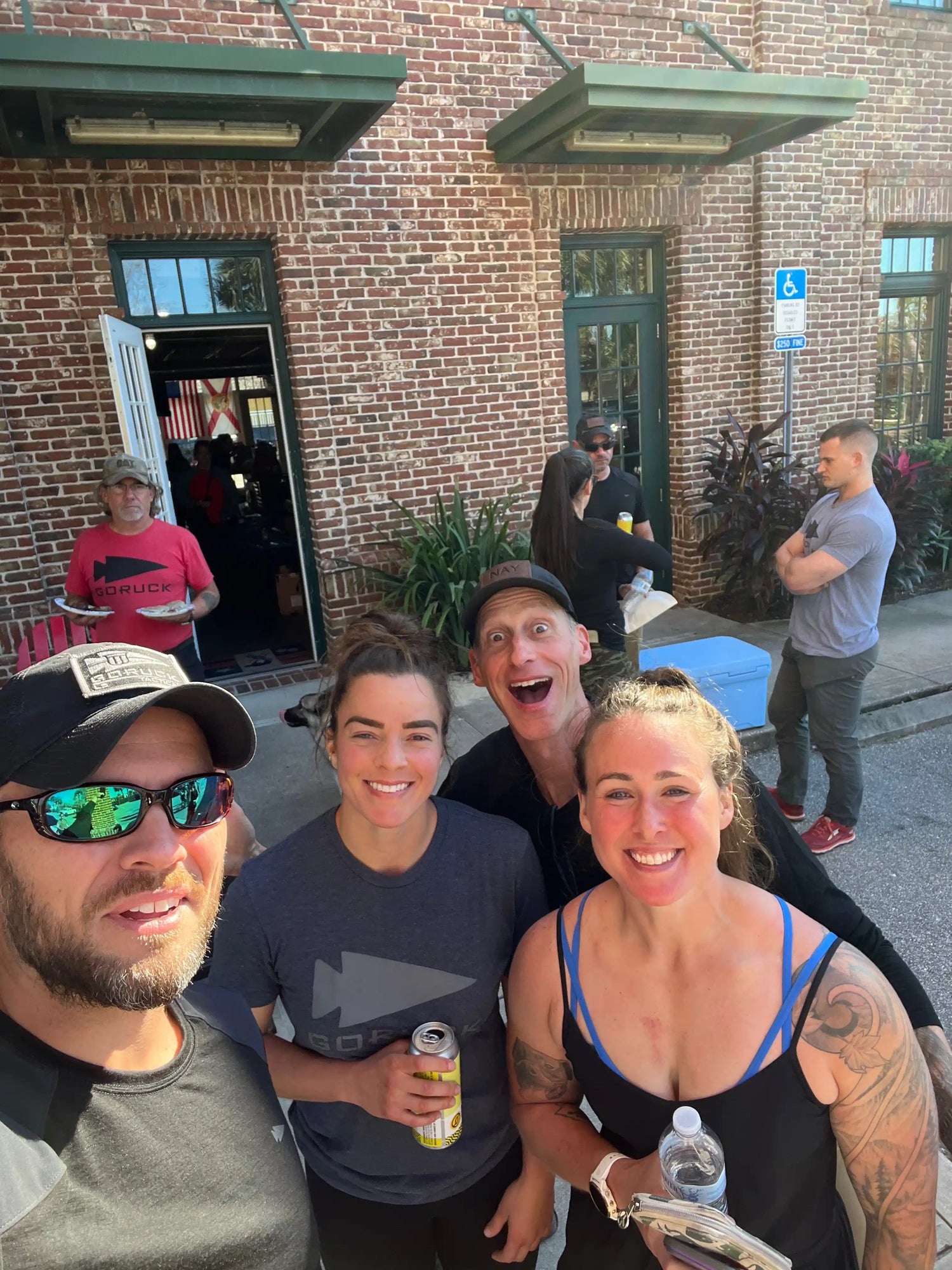 Group of smiling people in GORUCK gear outside brick building at a rucking event