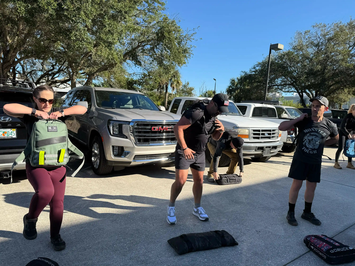 Group outdoor workout with GORUCK rucksacks in a parking lot, people exercising together