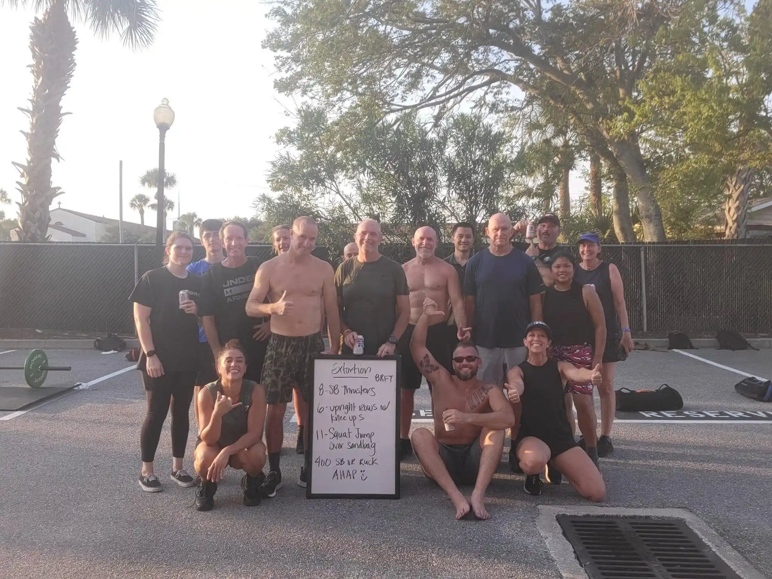 GORUCK group post-workout selfie outdoors with fitness whiteboard and exercise gear