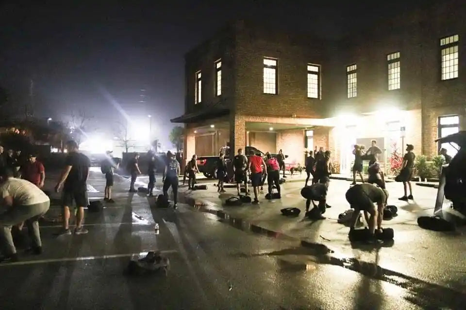 Group rucking workout at night outside brick building, GORUCK fitness community event