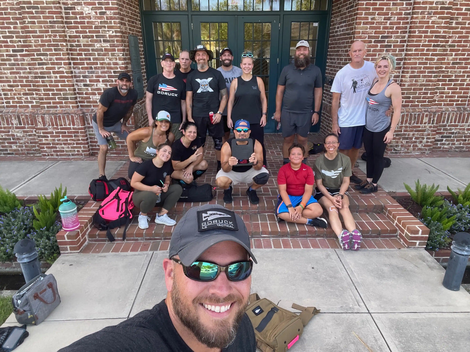 GORUCK team smiling after training, group on front steps with rucks and gear bags