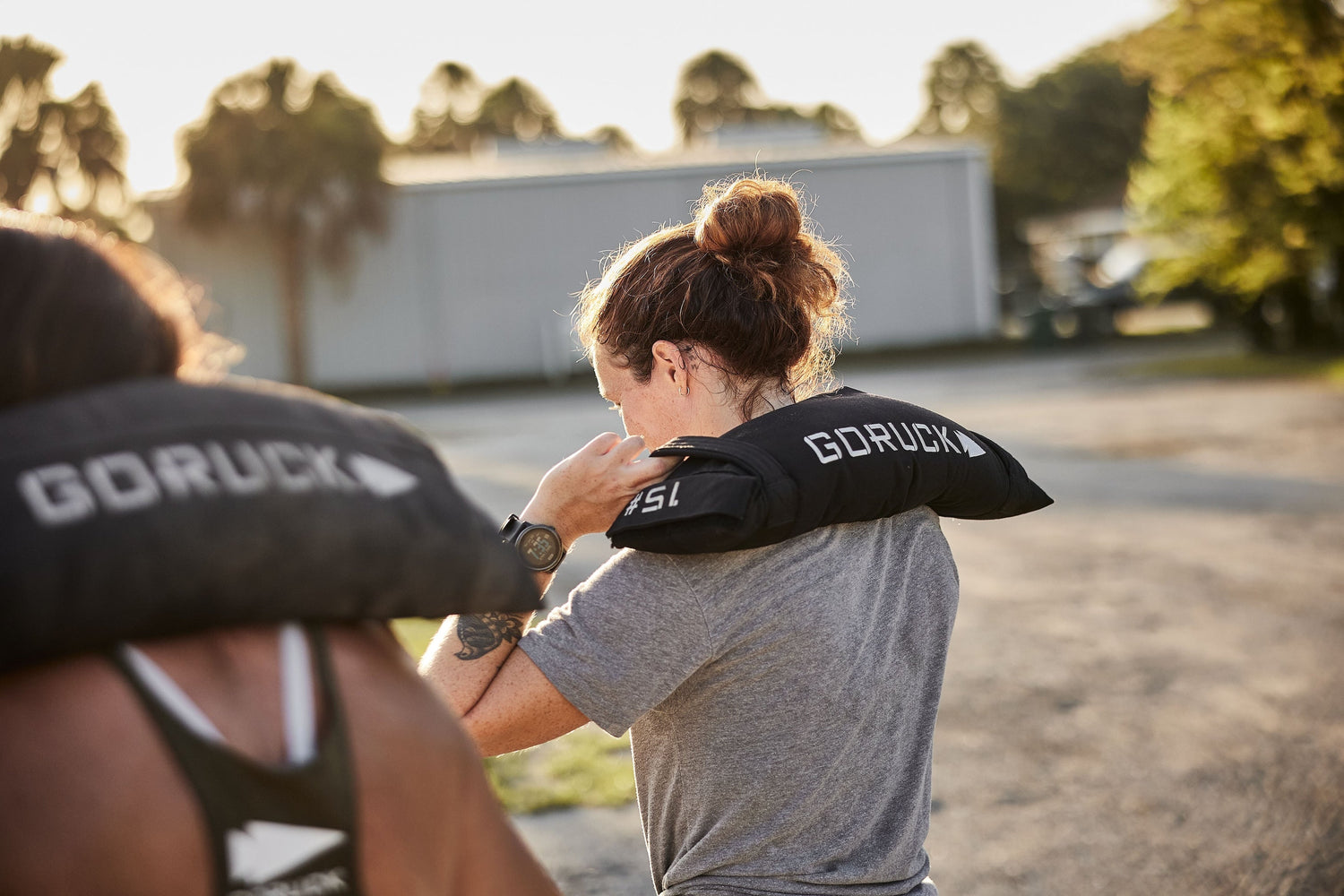 Two people rucking outdoors with GORUCK weighted sandbags on their shoulders