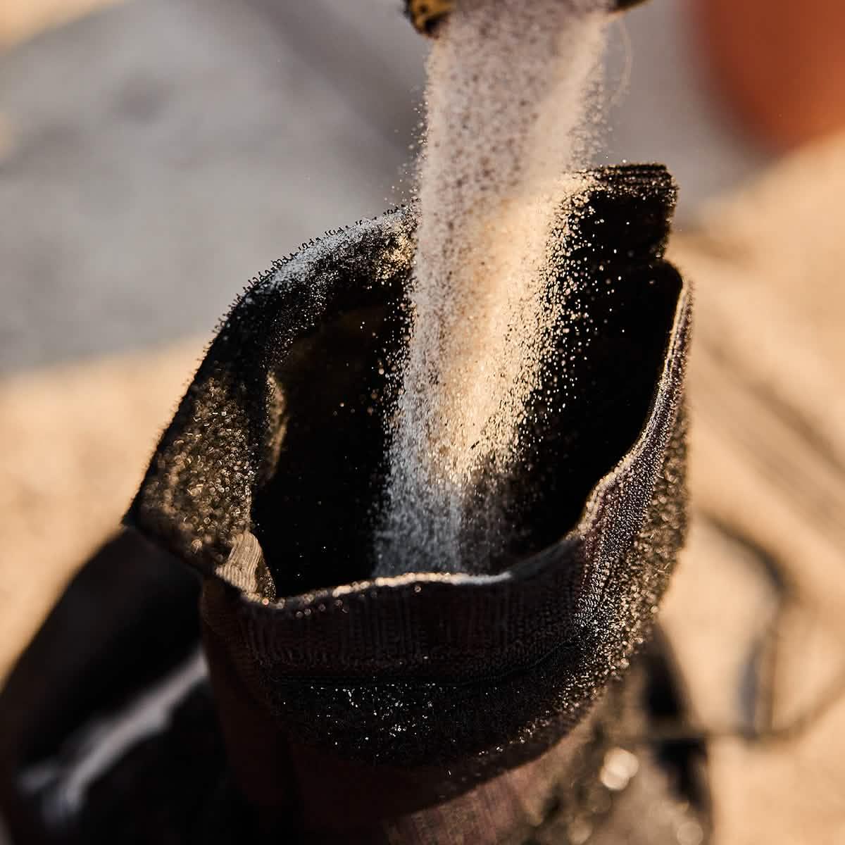 Sand being poured into a durable black GORUCK rucksack sandbag outdoors