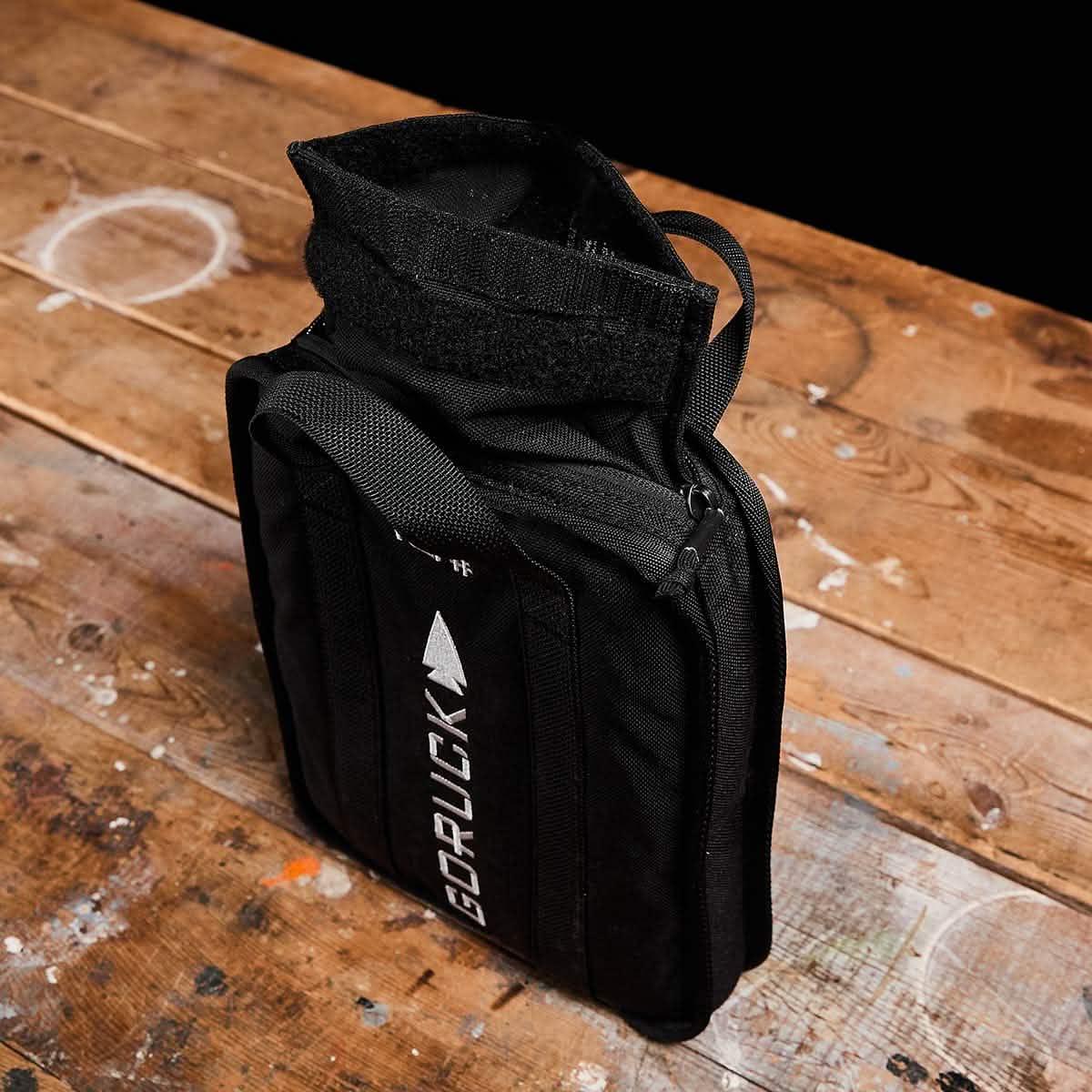 GORUCK black ruck plate carrier bag on rustic wooden table, durable rucking gear