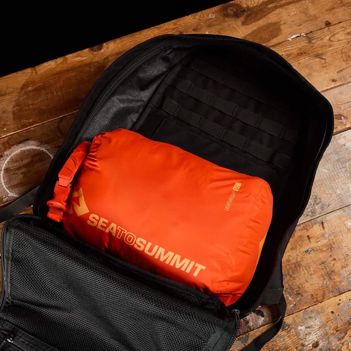 GORUCK rucksack with orange Sea to Summit dry bag inside on wooden surface