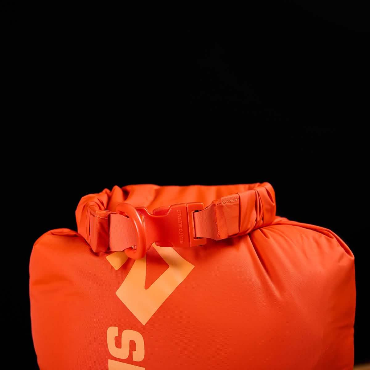 Bright orange GORUCK rucking dry bag with secure buckle closure, against black background