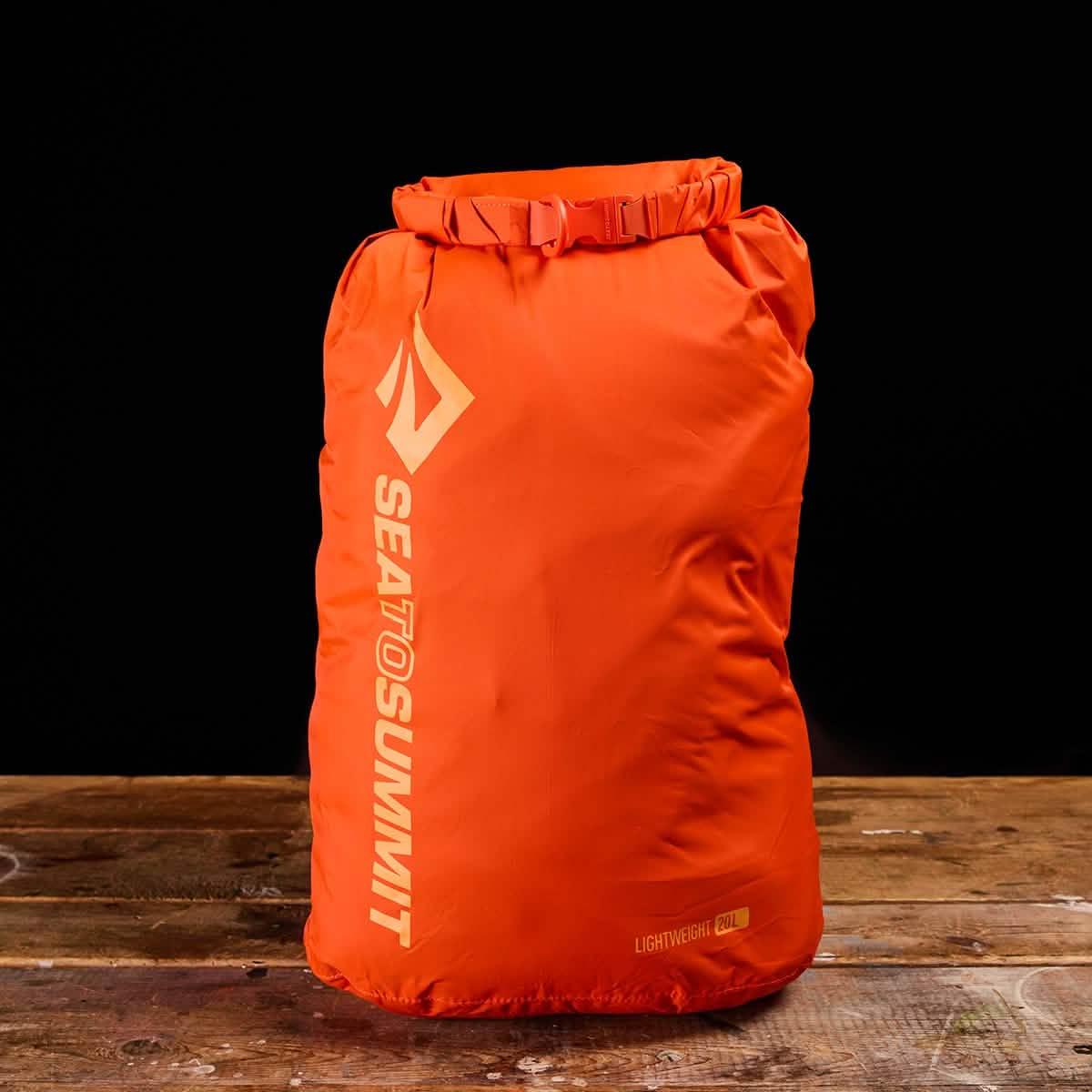 Sea to Summit orange lightweight dry bag on wooden surface, GORUCK outdoor gear