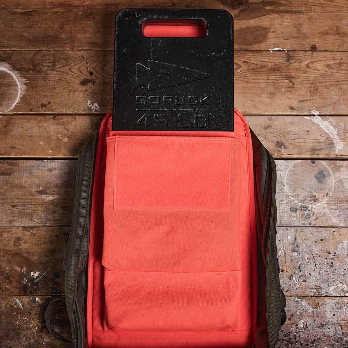 GORUCK 45 LB ruck plate in red backpack on wooden surface, rucking gear
