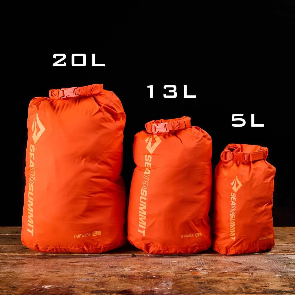 Three orange Sea to Summit dry bags in 20L, 13L, and 5L sizes for rucking gear