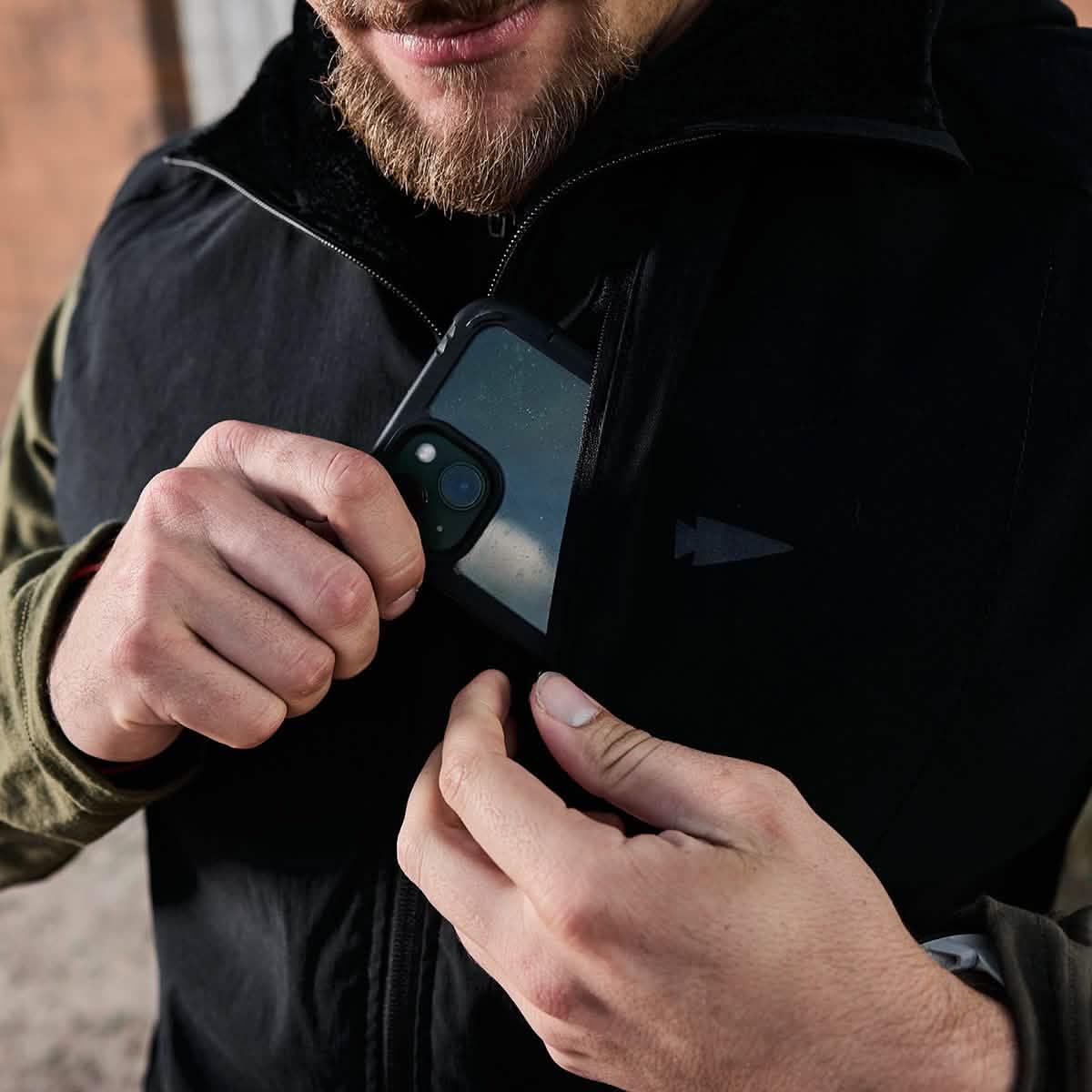 Man putting phone in GORUCK jacket chest pocket, rugged outdoor apparel detail