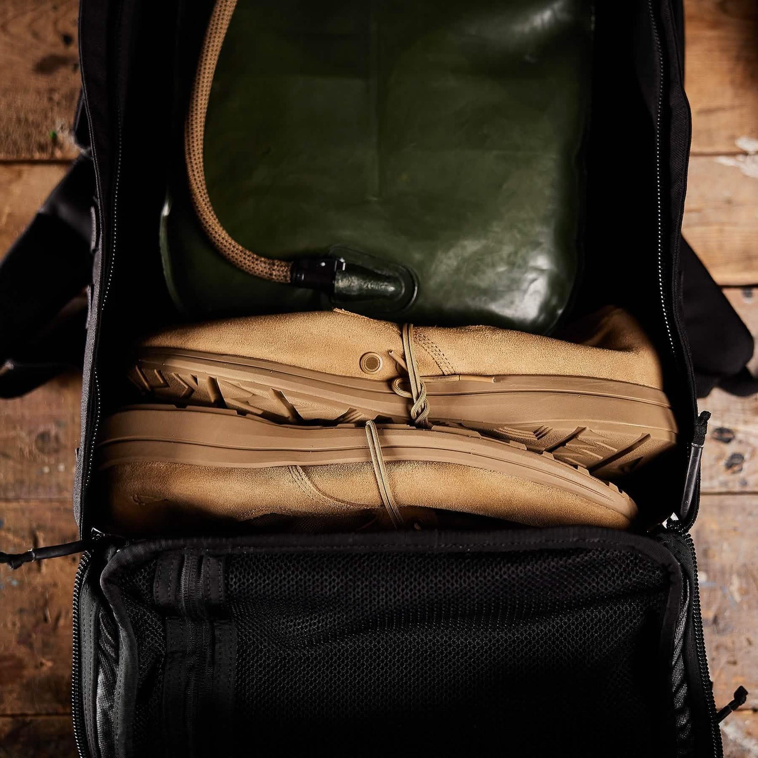 GORUCK rucksack open showing tan boots and green hydration bladder packed for rucking