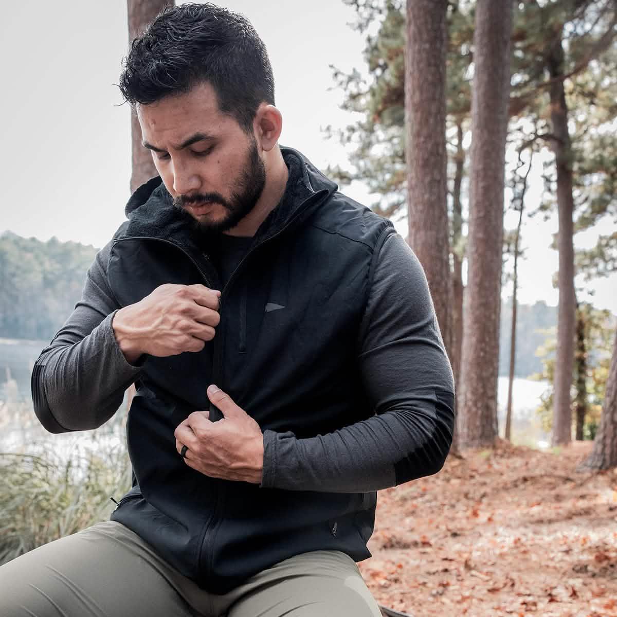 Man wearing GORUCK rucking vest outdoors in pine forest by a lake