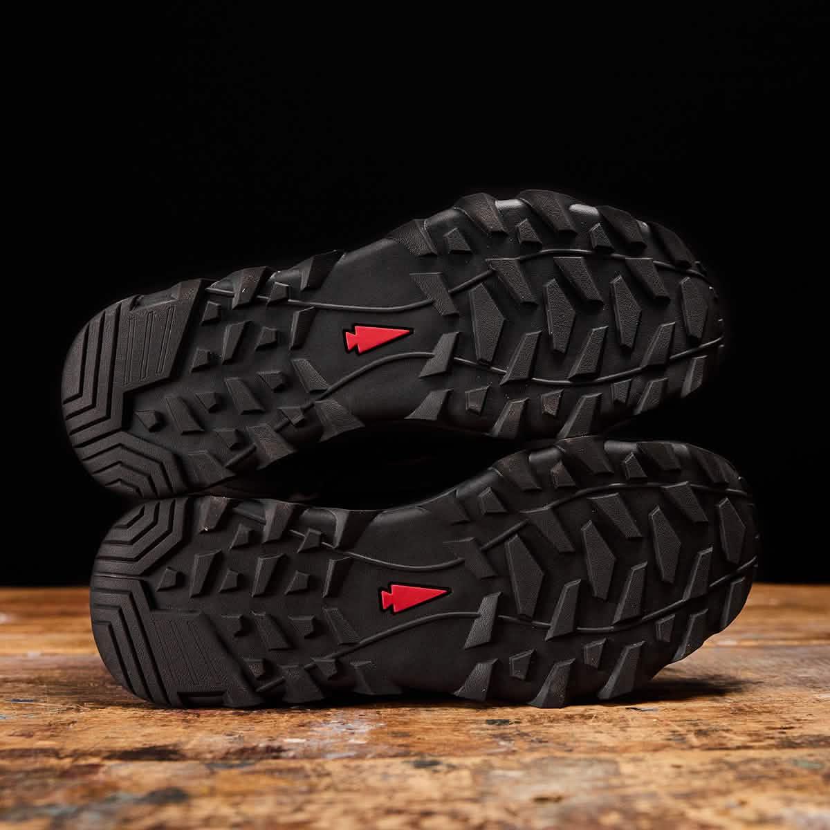 GORUCK rucking boots with rugged soles and red arrowhead logo on wooden surface