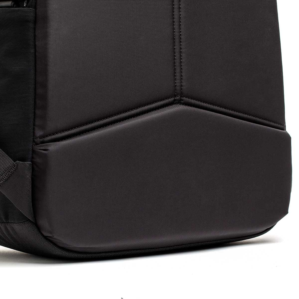 Close-up of the bottom corner of a black backpack with geometric stitching detail.
