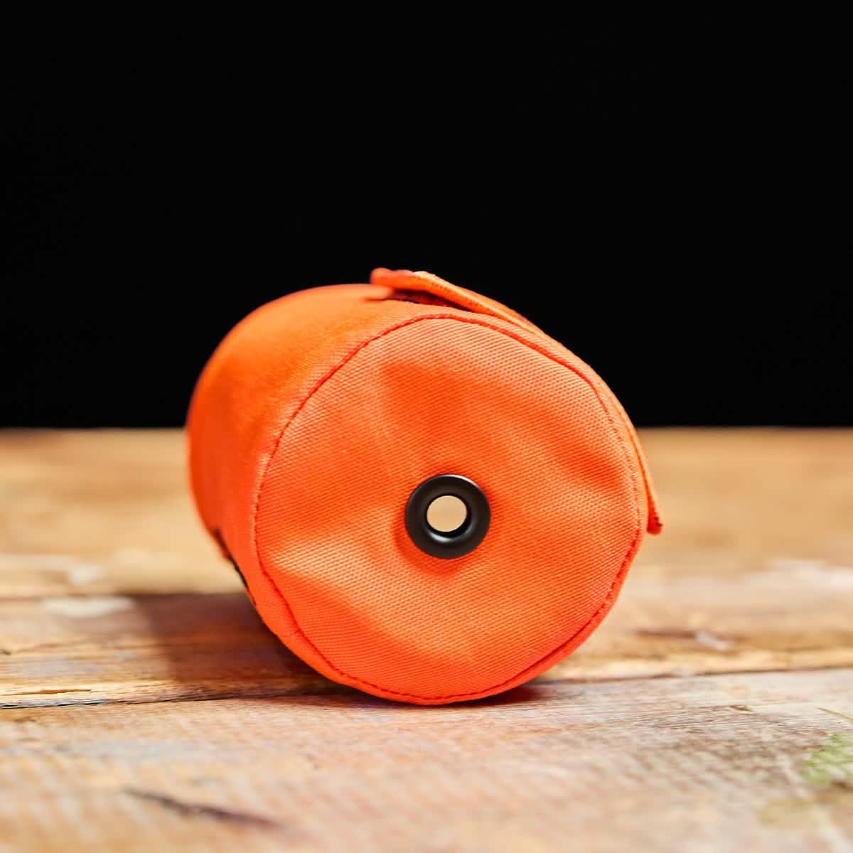 GORUCK orange beer jacket bottle cover on wood table, rugged outdoor gear accessory