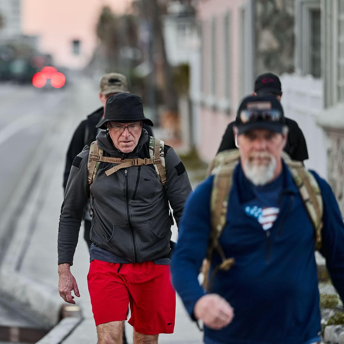Group of men rucking in GORUCK gear, urban sidewalk, wearing black boonie hats, backpacks
