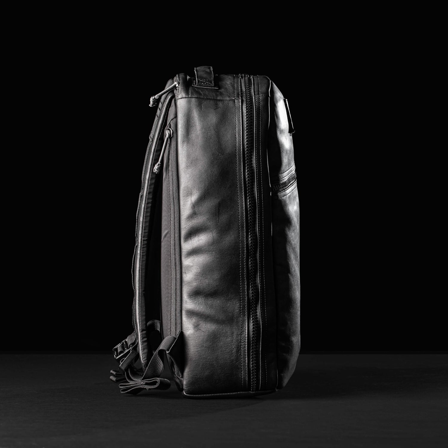 GORUCK Bullet 15L black leather backpack upright on black background, highlighting rugged design
