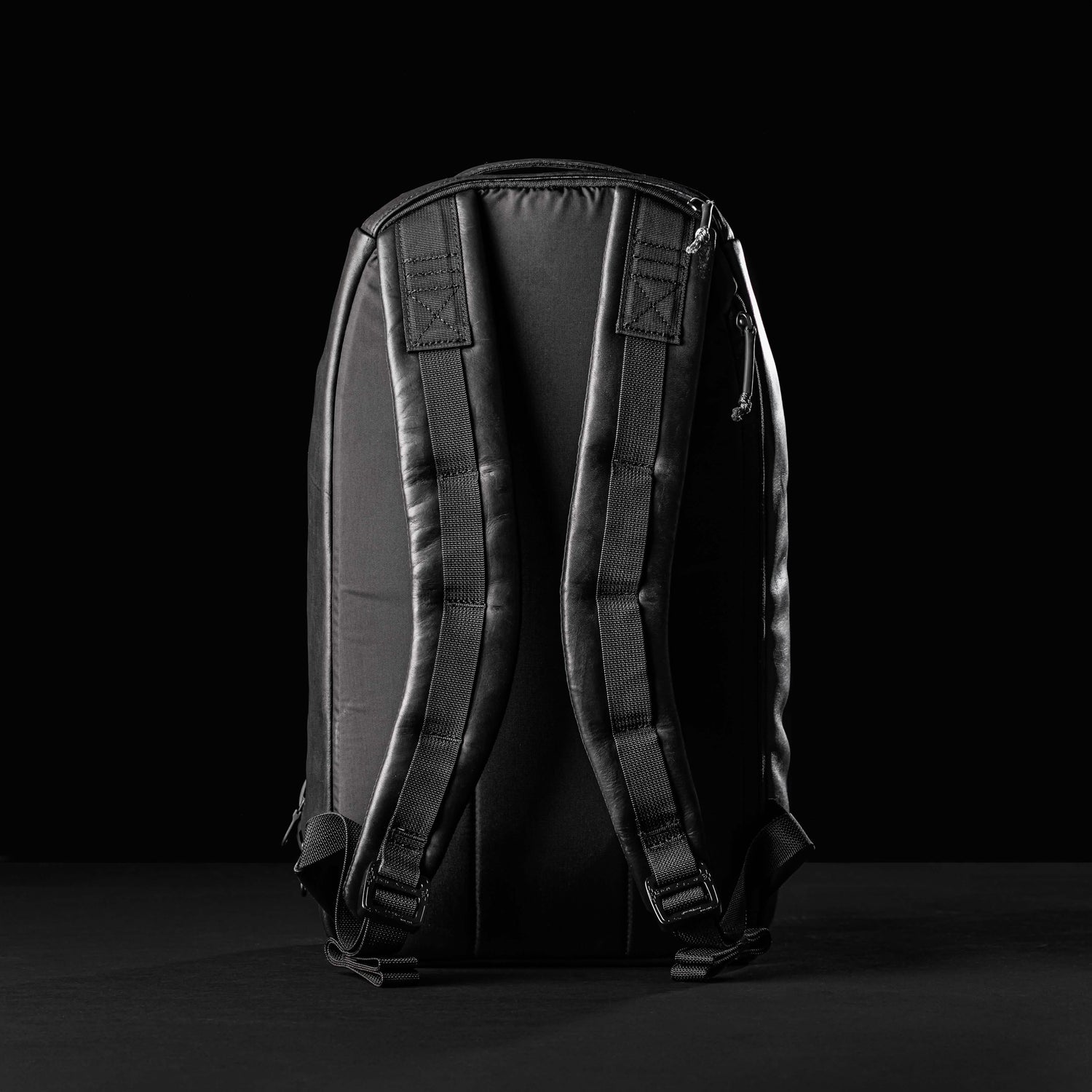 GORUCK Bullet 15L black leather backpack back view with padded straps on black background