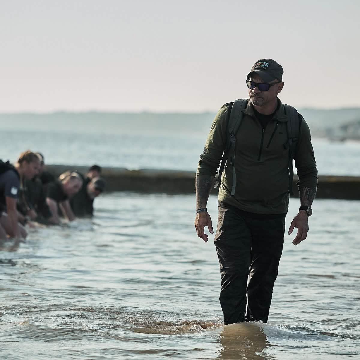 Man in GORUCK gear leading group rucking through water during outdoor endurance event
