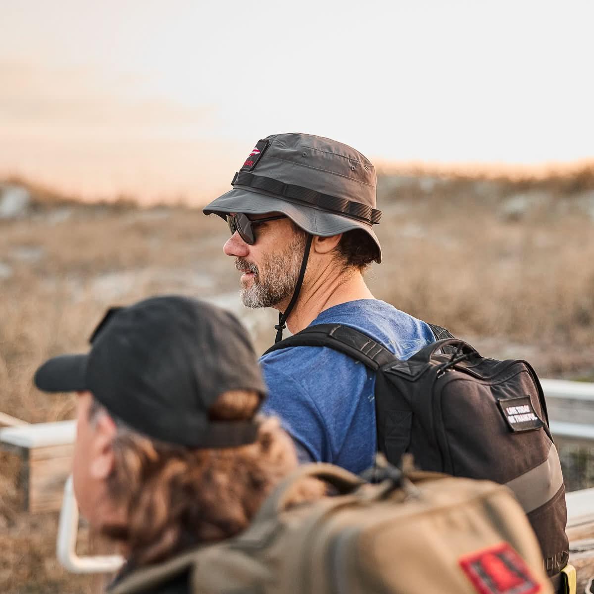 Man wearing GORUCK charcoal boonie hat and backpack outdoors during rucking activity