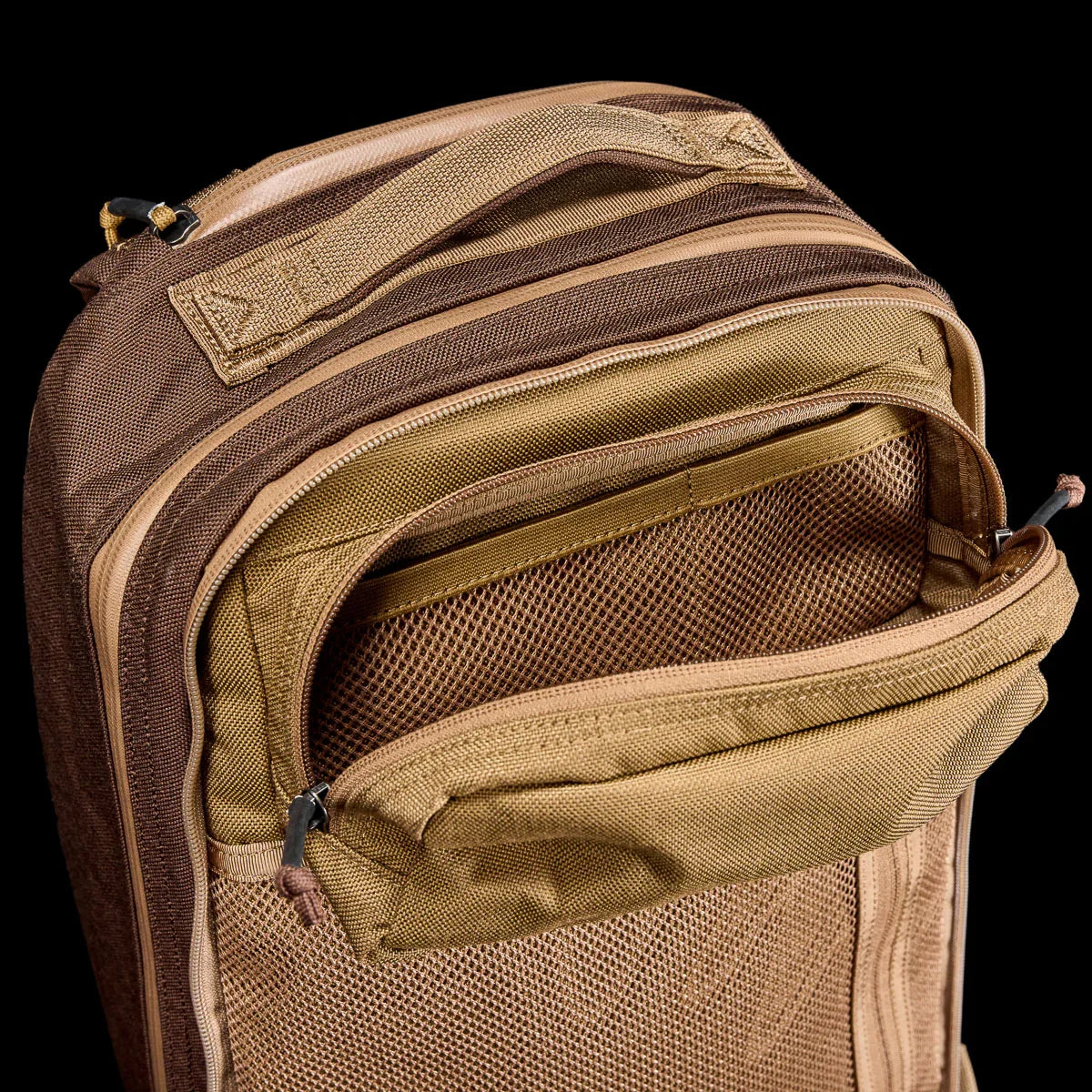 GORUCK tan rucksack with open mesh pocket, durable handle, and rugged zippers on black background
