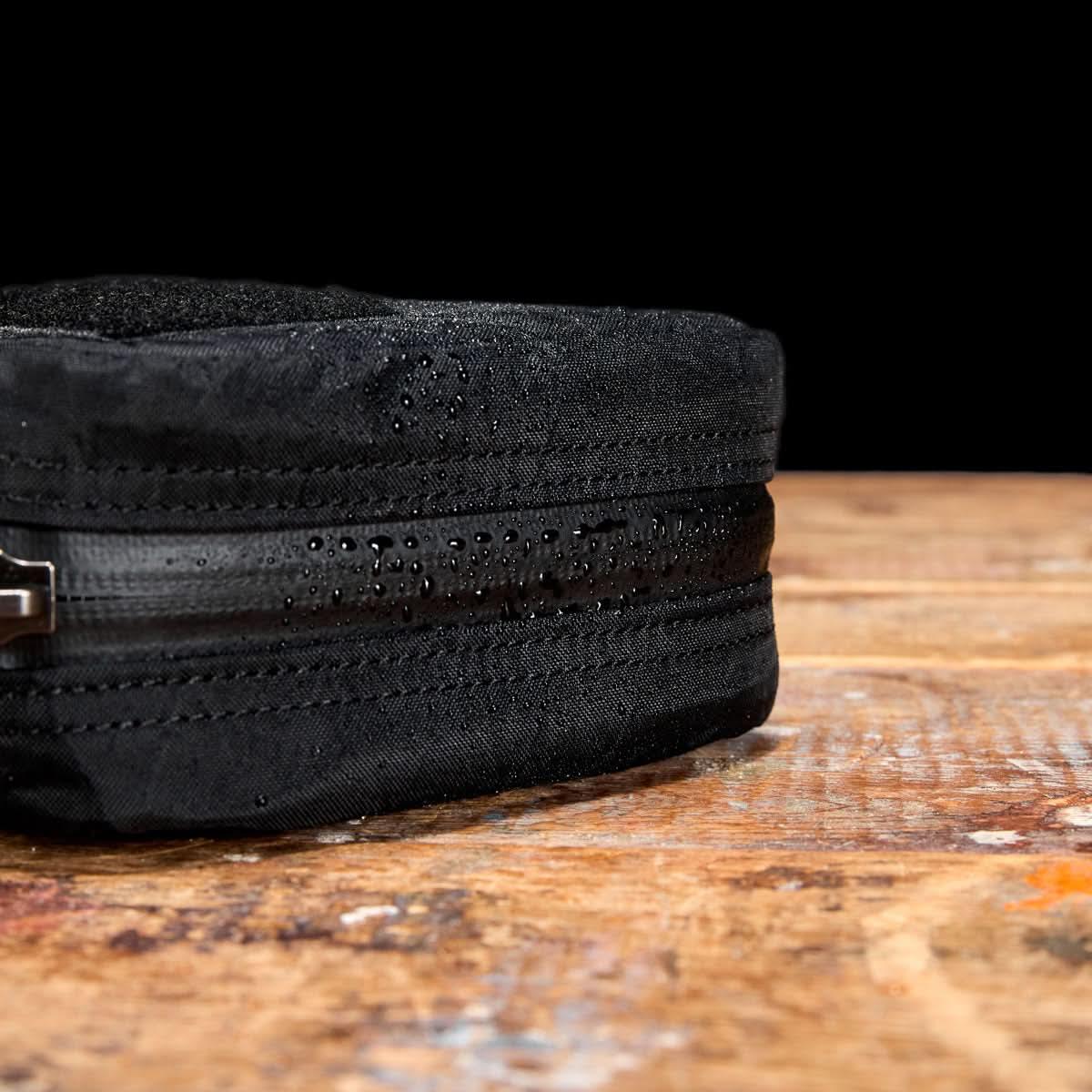 GORUCK black rucking pouch with water-resistant zipper on a rustic wooden surface