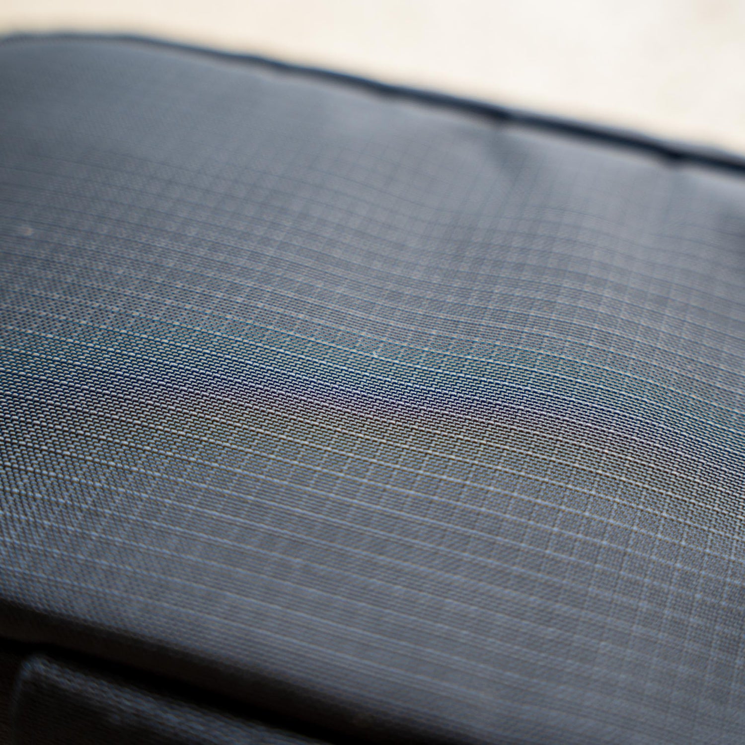 Close-up of IFAK (Black + Red Thread + Grey Interior + Red Patch) ROBIC w/ Aquaguard fabric featuring textured dark gray surface, faint grid lines, and a subtle iridescent sheen.