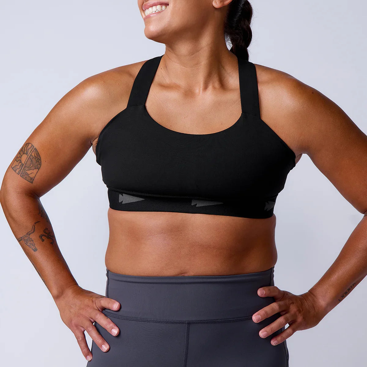 Athletic woman wearing GORUCK black sports bra and grey workout leggings, studio setting