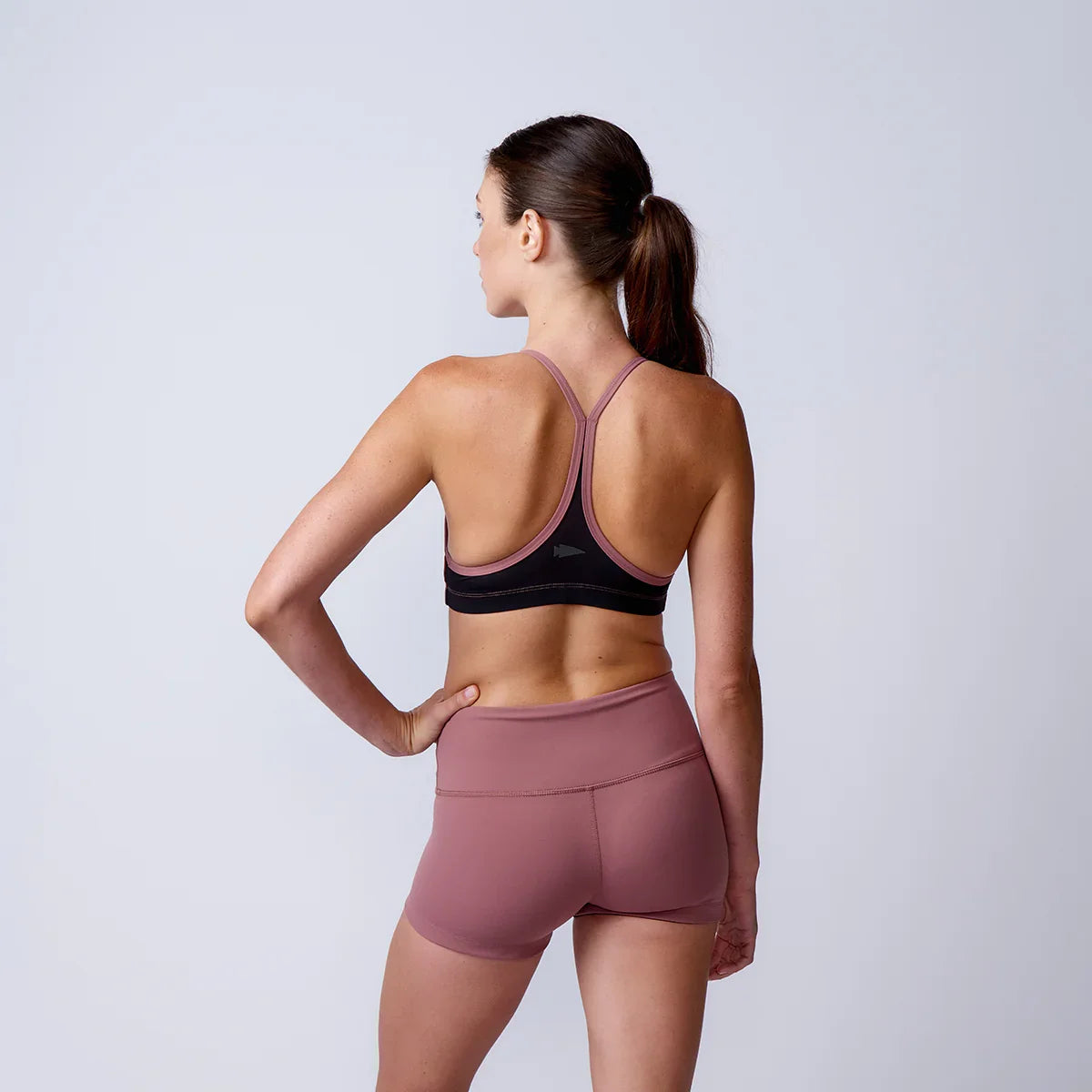 Woman modeling GORUCK rucking sports bra and shorts, studio back view, athletic wear