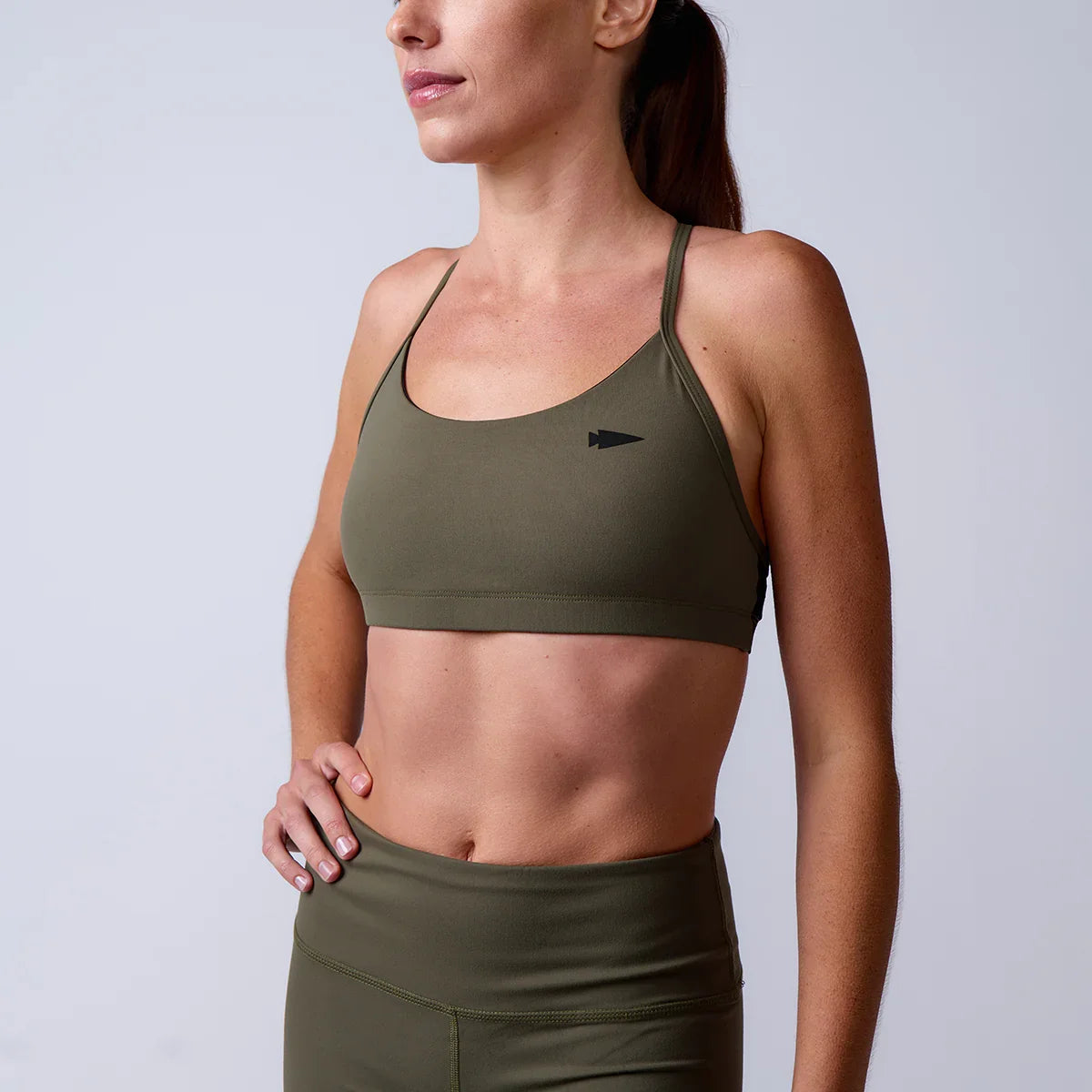 Woman wearing olive green GORUCK sports bra and leggings, studio background