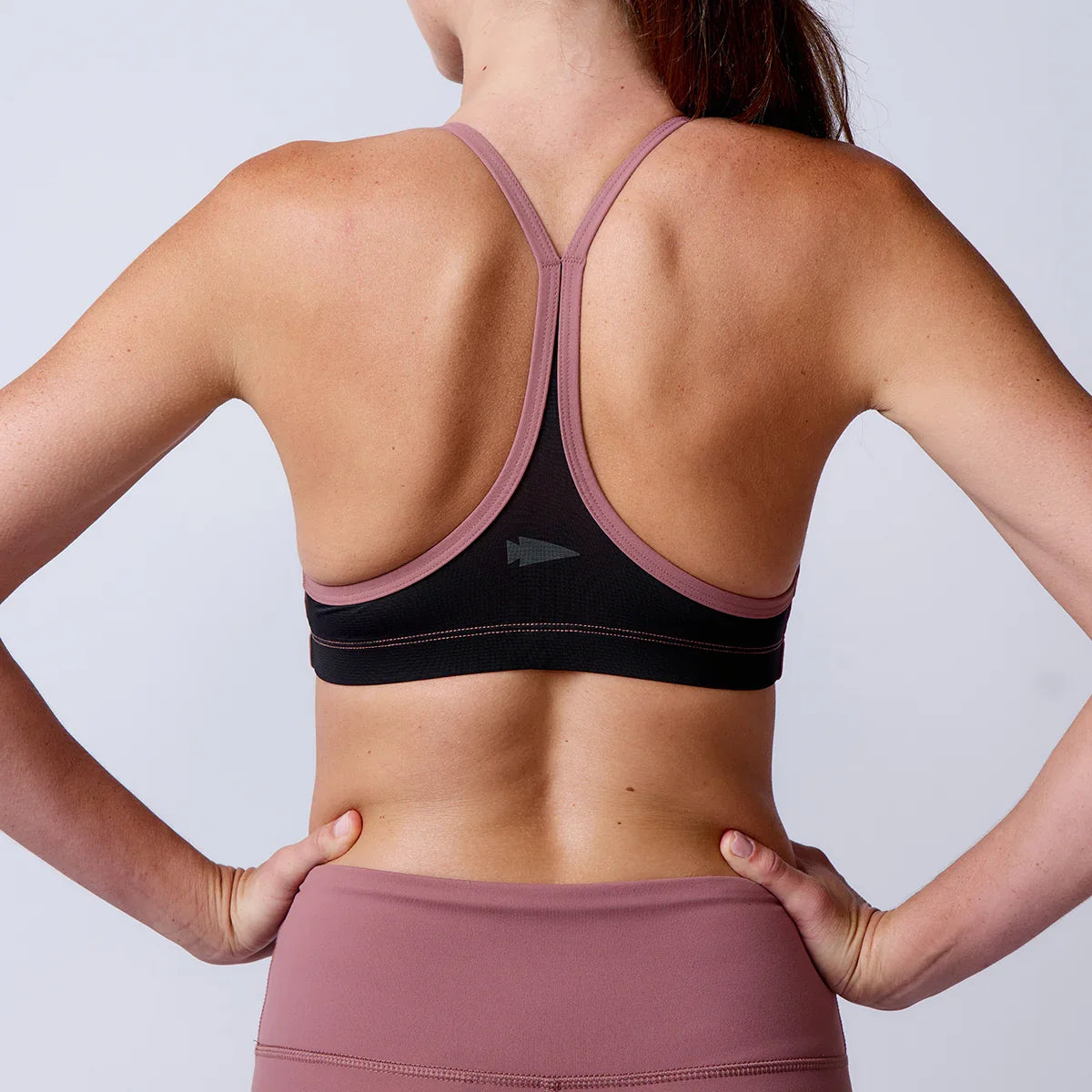 Woman wearing GORUCK rucking sports bra and leggings, back view, fitness apparel