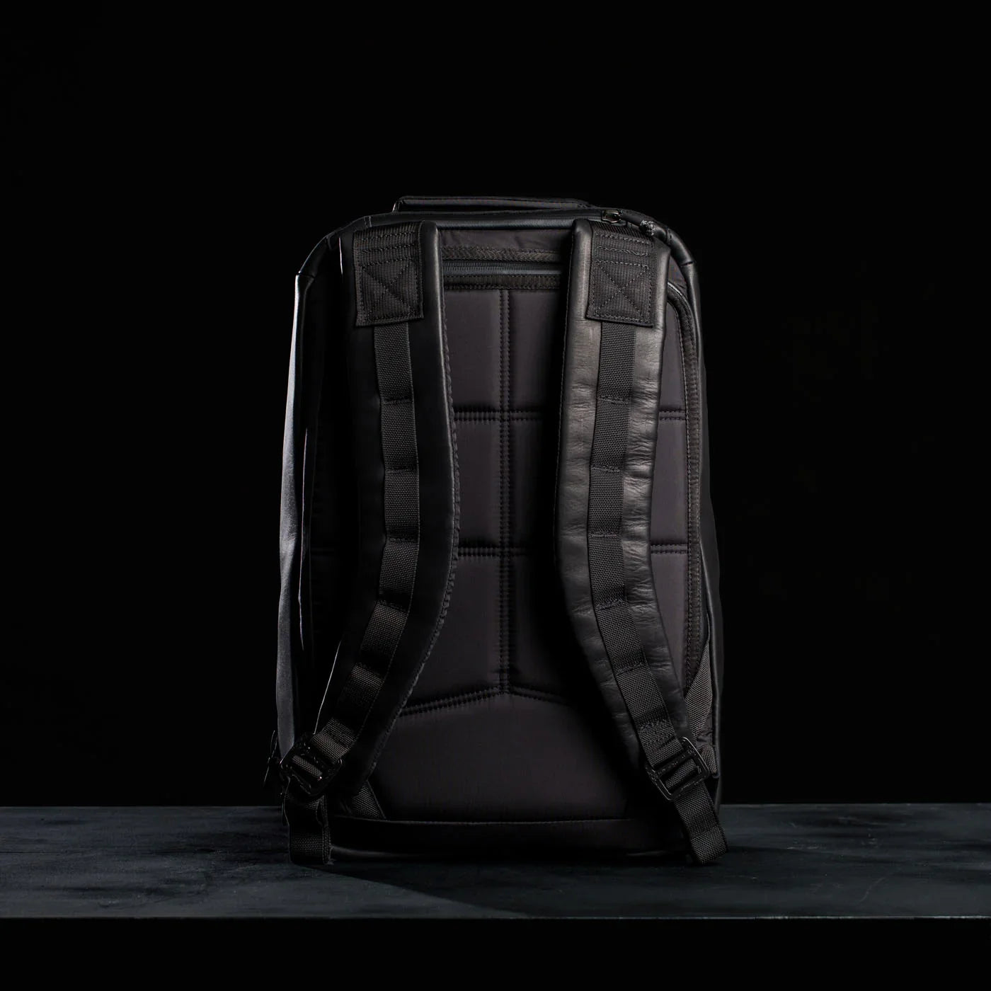 GORUCK black leather rucksack with padded straps and rugged design, back view on black
