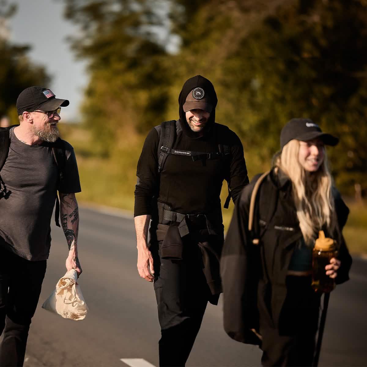 Three people rucking outdoors in GORUCK gear and hoodies, walking on a sunny road
