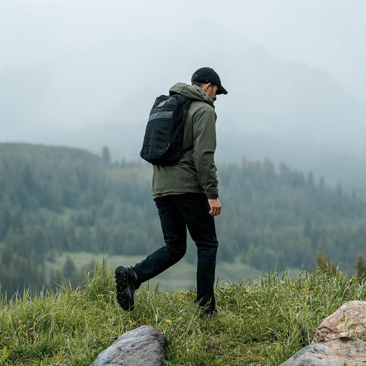 Man rucking outdoors in misty mountains, wearing GORUCK backpack and outdoor gear