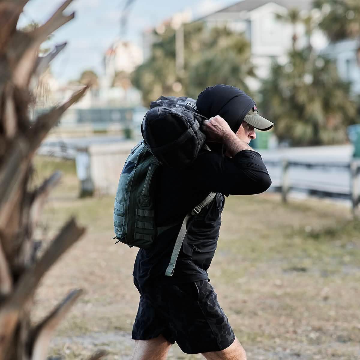 Man rucking outdoors in black GORUCK ToughMesh hoodie with backpack and sandbag