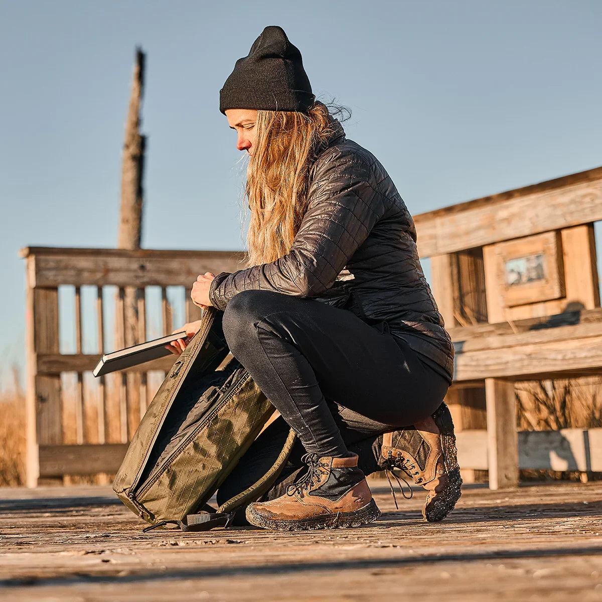 Woman outdoors in GORUCK MACV-2 Mid Top Chestnut Black boots, packing an olive rucksack
