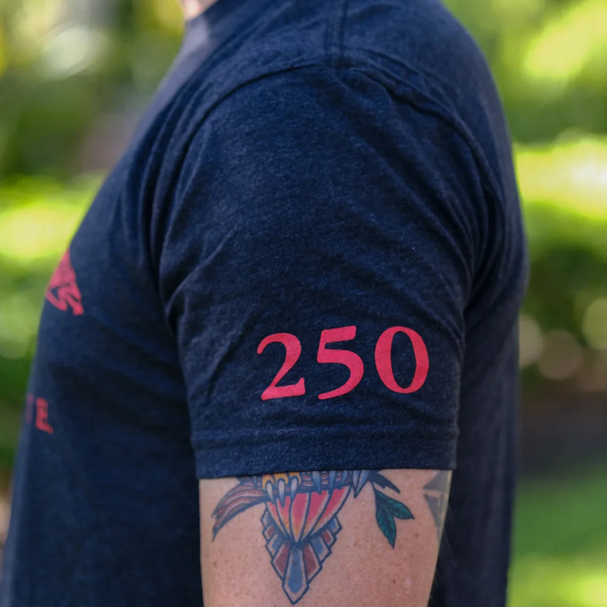 GORUCK navy t-shirt with red 250 graphic on sleeve, person with colorful arm tattoo