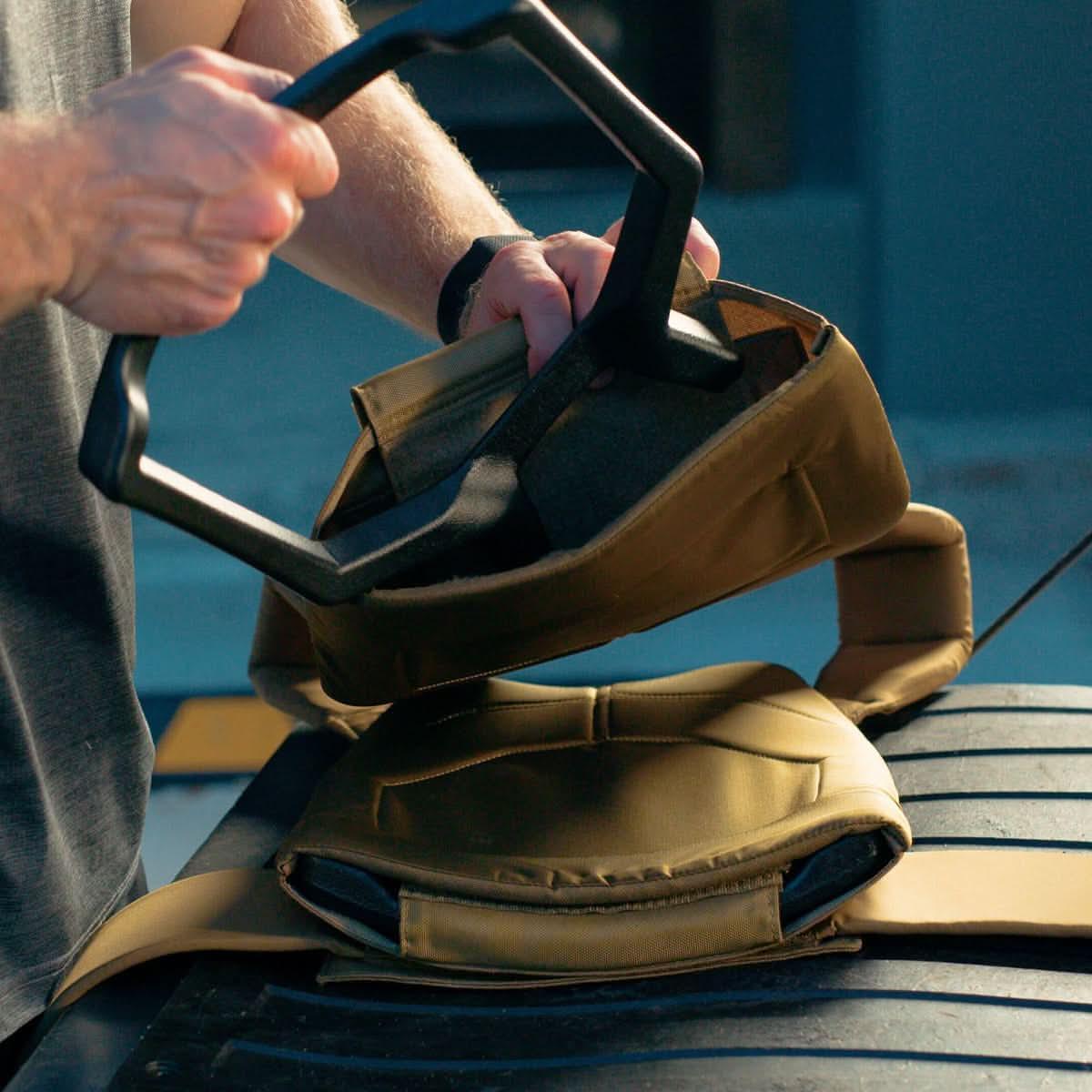 Person loading weighted plate into GORUCK rucking vest outdoors