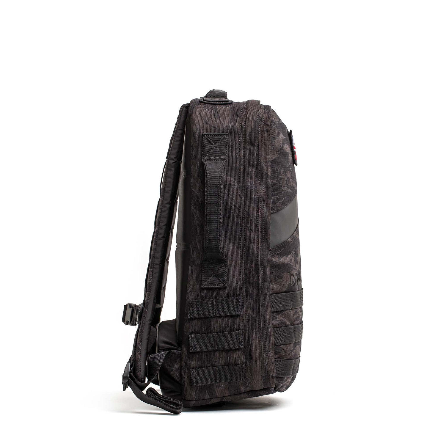 Side view of the Rucker 5.0, a black camouflage rucksack with multiple straps and handle, designed for rucking and enhanced lumbar support, standing upright on a white background.
