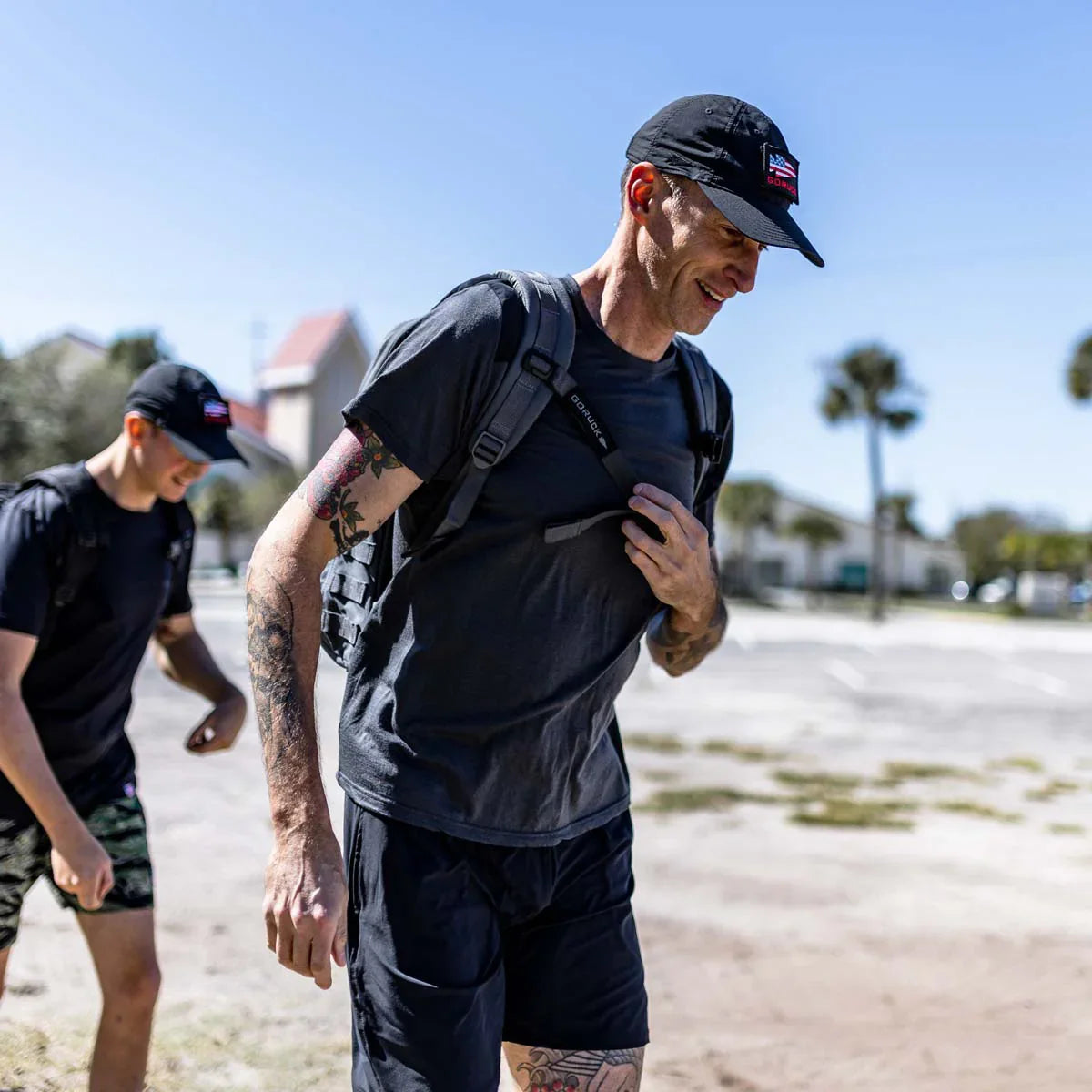 Two men rucking outdoors with GORUCK backpacks and sternum straps in sunny weather.