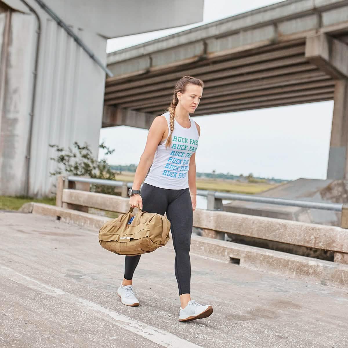 Woman rucking outdoors with GORUCK training gear under bridge