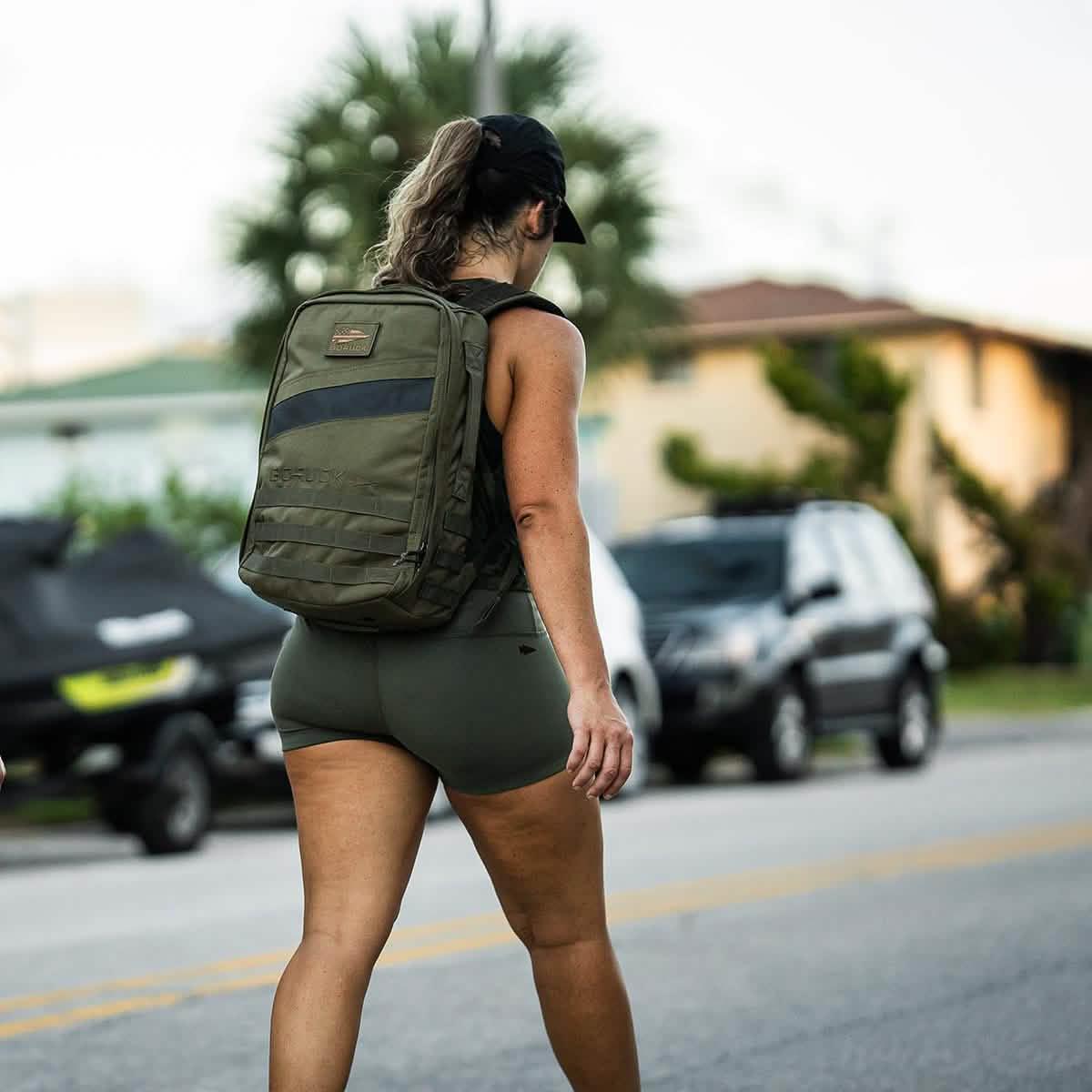 Woman wearing ToughFlex Ranger Green squat shorts and GORUCK backpack walking outdoors