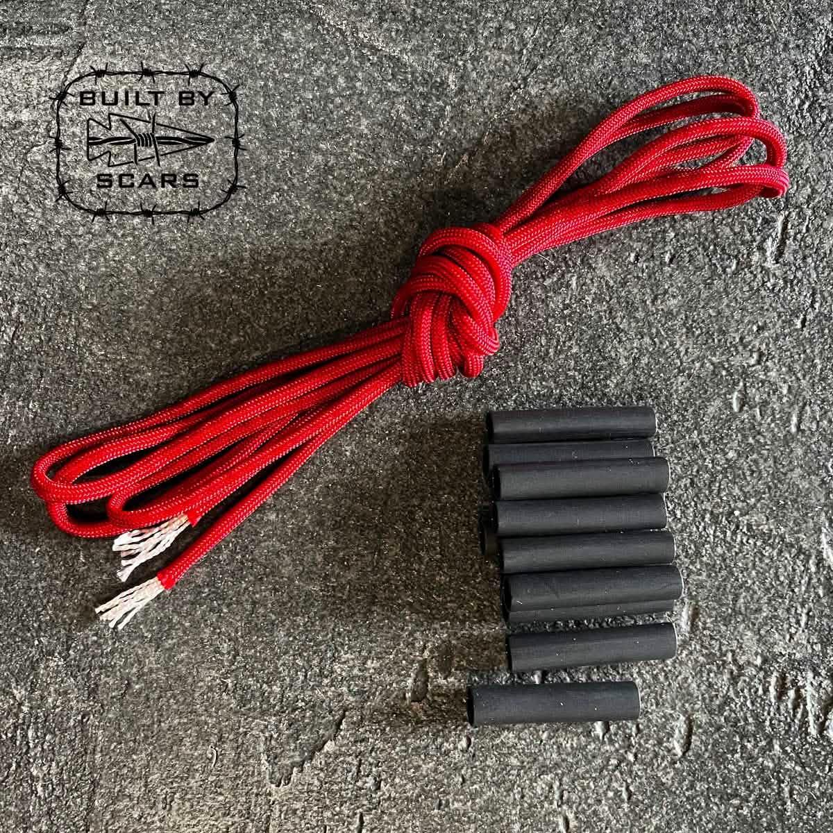 GORUCK red paracord and black heat shrink tubing kit on stone background, Built by Scars logo visible.