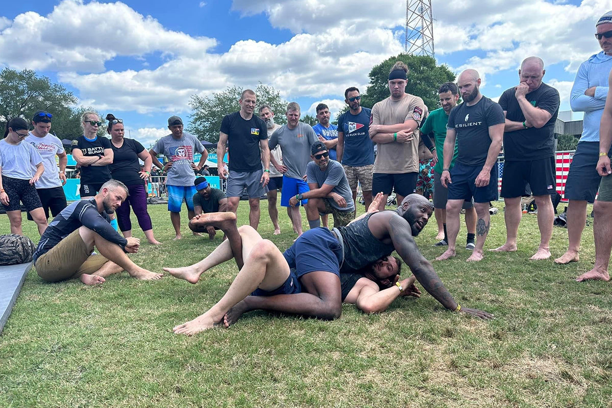 Group watches outdoor grappling demonstration at GORUCK rucking fitness event on grass